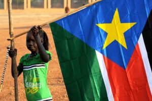 1280px-A_young_girl_hangs_the_South_Sudan_flag_(5925619011)